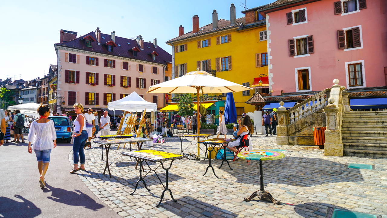 street with tables and unbrella's surrounded by colourful hotels